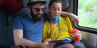 一对夫妇在火车上用平板电脑上网