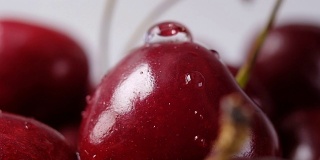 一颗成熟的樱桃滴水而下。近距离微距镜头，慢动作。