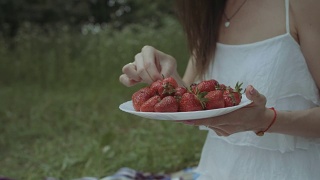 野餐时吃草莓的快乐女人视频素材模板下载