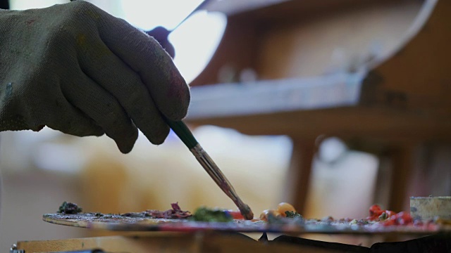 手的女艺术家在手套画画与油画颜料。在工作室工作的天才女孩的过程。混合颜色。4 k
