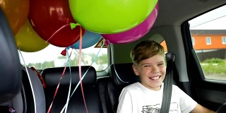 快乐的孩子在车里。喜庆心情，笑一笑，欢声笑语。汽车里的气球