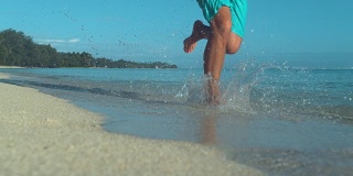 低角度:一个面目全非的男人赤脚跑在美丽的白色沙滩上。