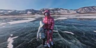 家人在白天滑冰。女孩们在大自然中骑着花样滑冰鞋。母亲和女儿一起骑在裂缝中的冰上。冬季户外运动对运动员来说是一种乐趣。
