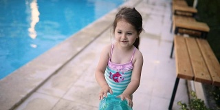 漂亮的幼童在游泳池里玩一个游泳圈