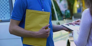 女士签署快递证明表格，并从快递员那里收到黄色包裹