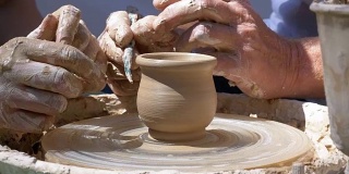 陶工大师的双手和陶工轮上的粘土花瓶