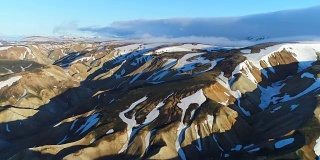 山谷国家公园landmanalaugar的4k航拍。平缓的山坡上是雪原和冰川。壮丽的冰岛在夏天