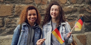 快乐的德国学生的慢动作肖像漂亮的女孩挥舞着德国国旗，看着镜头笑。友谊、旅游、快乐的人理念。