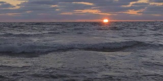 美丽的日落在海滩上，惊人的颜色，光束透过云景在海景。海上日落。海滩上的日出。海滩上的日落。在海上日落。海上日出