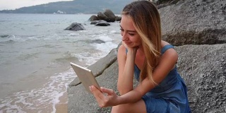 慢镜头年轻的妻子在海边用平板电脑和朋友交流