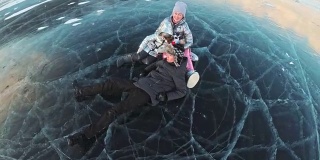 一家人在裂缝里美丽的冰上玩得很开心。爸爸妈妈儿子和女儿在冰上打闹，做三明治休息。男人、女人和孩子们正在贝加尔湖上休息。