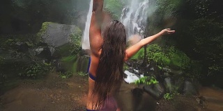 年轻性感的女人在看丛林中的瀑布。生态旅游