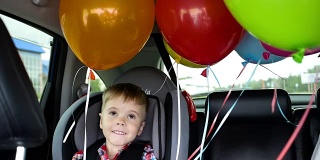 快乐的孩子在车里。喜庆心情，笑一笑，欢声笑语。汽车里的气球。孩子的生日