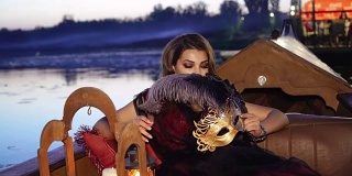 戴着狂欢节面具坐在贡多拉上的漂亮女人。