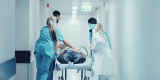 急诊科:医生，护士和护理人员跑和推轮床/担架与严重受伤的病人走向手术室。明亮的现代医院，专业人员挽救生命。