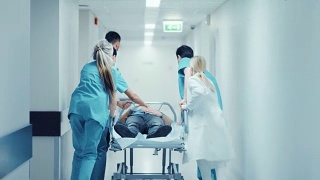 急诊科:医生，护士和护理人员跑和推轮床/担架与严重受伤的病人走向手术室。明亮的现代医院，专业人员挽救生命。视频素材模板下载