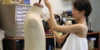 亚洲女性时装或设计师与裁减人体模特工作的一卷织物