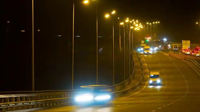 公路交通车辆在夜间时间流逝。汽车在桥上行驶的晚上时间流逝。4 k UHD