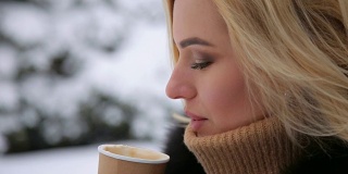 白雪覆盖的公园里喝着咖啡的女孩的肖像。