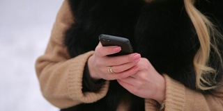 一个女孩在冬天拿着手机的特写。