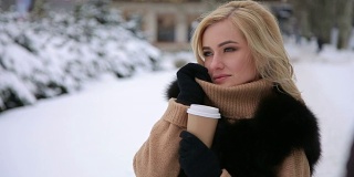 白雪覆盖的公园里喝着咖啡的女孩的肖像。