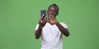 年轻的非洲男子用绿色背景的手机视频通话