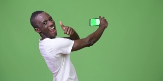 年轻的非洲男子用绿色背景的手机视频通话