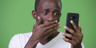 年轻的非洲男子在使用电话时看起来很震惊