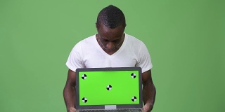 年轻的非洲男子在展示笔记本电脑时看起来很震惊