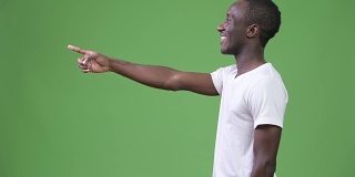 侧面视图的年轻快乐的非洲人对绿色的背景