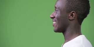 侧面视图的年轻快乐的非洲人对绿色的背景