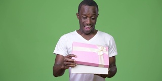 年轻快乐的非洲男子在打开礼盒时看起来很惊讶