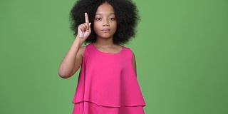年轻可爱的非洲女孩与非洲发式指着手指向上