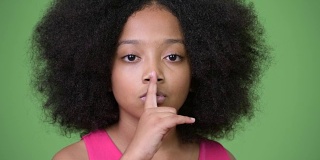 年轻可爱的非洲女孩手指放在嘴唇上