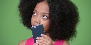 年轻可爱的非洲女孩与非洲发型使用电话和思考