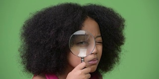 年轻可爱的非洲女孩与非洲发式使用放大镜