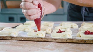 专业的面包师在放入烤箱前在甜烤面包上添加果酱视频素材模板下载