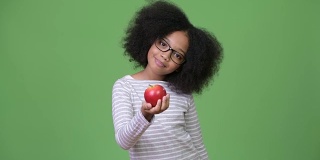 年轻快乐的非洲女孩，留着非洲式的头发，拿着苹果