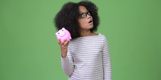 年轻可爱的非洲女孩与非洲发型拿着小猪银行