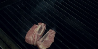 厨长用金属钳子将生肉放在热气腾腾的烤架上，下面是火，特写慢镜头。