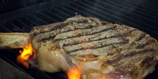 厨长用金属钳子将生肉放在热气腾腾的烤架上，下面是火，特写慢镜头。