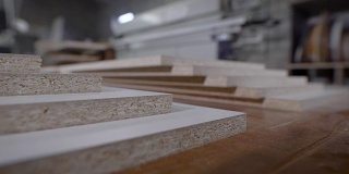 细木工店里的工作台上放着切好的刨花板，这是家具厂的移动特写镜头