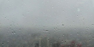 透过玻璃窗外的城市景观与雨滴在摩天大楼
