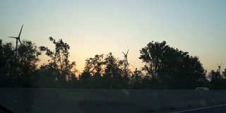 在日落时分，在高速公路上驾驶着风车