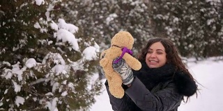 冬天，怀孕的女孩和泰迪熊在公园里。