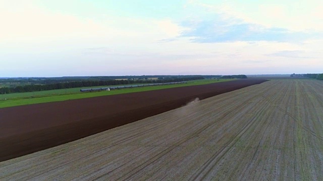 4K无人机航拍镜头。拖拉机耕地。以train为背景