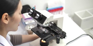 在实验室里用显微镜和药片工作的科学家