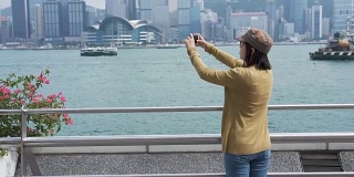 女游客在香港维多利亚港拍照