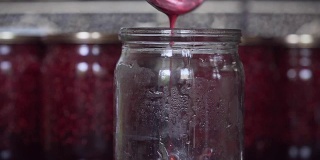女人把覆盆子果酱倒在玻璃罐中保存