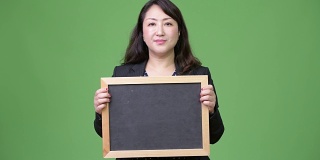 成熟美丽的亚洲女商人展示黑板